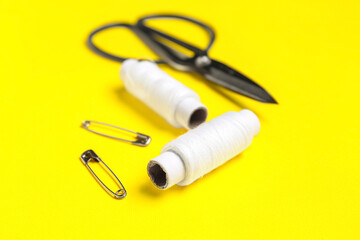 White thread spools on yellow background, closeup