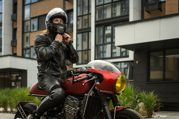 Biker wears safety helmet sitting on motorcycle - obrazy, fototapety, plakaty