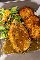 poultry meat with sauce served with hash browns and salad