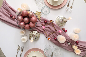 Christmas table setting with burning candles and balls in dining room, top view