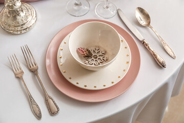 Christmas table setting with pink and white plates in dining room, closeup
