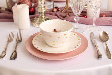 Fototapeta na wymiar Christmas table setting with pink and white plates in dining room, closeup