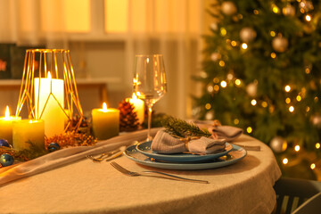 Christmas table setting with burning candles and fir branches in dining room