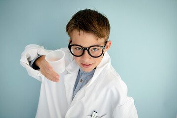 young cool boy ,with big massive black glasses is dressed up as a mad scientist holding beaker and vials in hand in front of blue background - Powered by Adobe