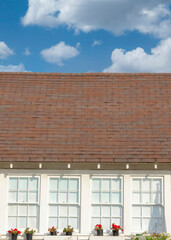Vertical White puffy clouds Small traditional gable house with USA flag at the front in La J