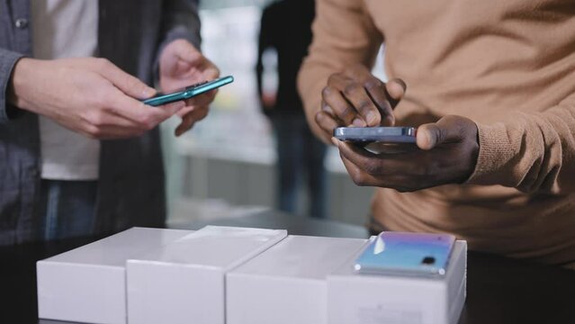 A consultant in an electronics store offers a choice of new smartphones to an African man.