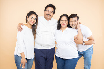 Happy indian family wearing white casual t-shirt sitting together isolated beige background.