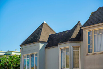 Beige stucco apartment building with multiple unit as a detail shot with copy space clear blue sky and brown castle style roofs
