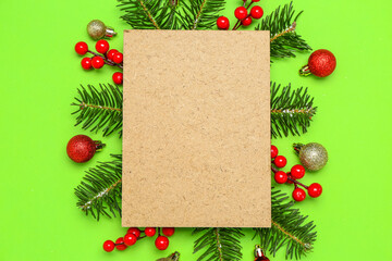 Composition with blank card, Christmas decorations and fir branches on green background
