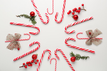 Frame made of tasty candy canes and Christmas decorations on white background