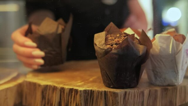 Close up footage of barmen bring chocolate muffin from shop.