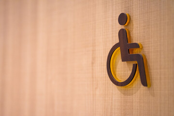 Wooden sign in front of a toilet for the disabled on a wooden background