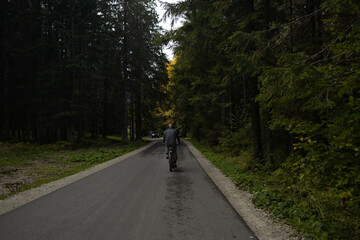Fototapeta na wymiar Male athlete mountain biker rides a bike on a forest path. Mysterious view. Autumn hike in the forest. Adventures in nature. Active lifestyle