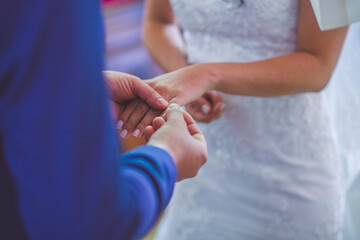 Obraz na płótnie Canvas groom putting wedding ring on bride's hand at a wedding
