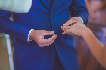 groom putting wedding ring on bride's hand at a wedding
