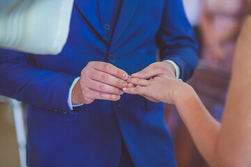 Fototapeta premium groom putting wedding ring on bride's hand at a wedding