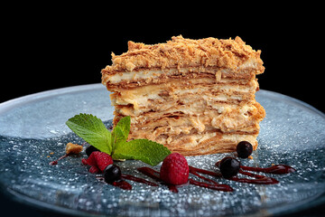 A piece of Napoleon cake with berries and mint