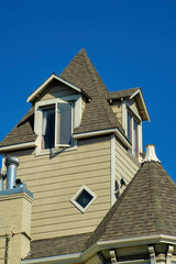 Wooden or timber house or home with beige wooden pannels and dark brown roof with tiles and visible open window with chimney