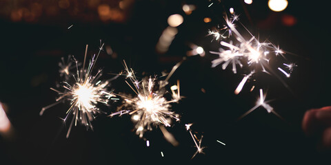 Sparklers on dark night sky. Bengal fire for christmas background with space for text.