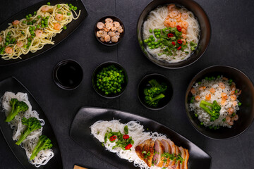 Various dishes of Asian cuisine with different types noodles and rice with shrimp, duck, vegetables and black sesame