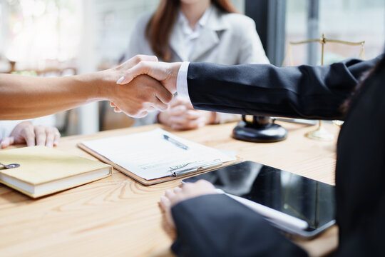 Law, consultation, agreement, contract, lawyer or  attorney shakes hands to agree on the client's offer to be hired to fight the parties in court.