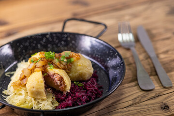 dumpllings filled with smoked meat served with red and white cabbage