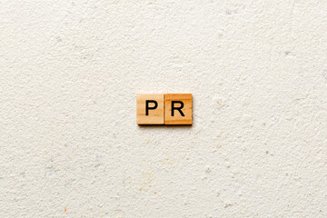 pr word written on wood block. public relation text on table, concept