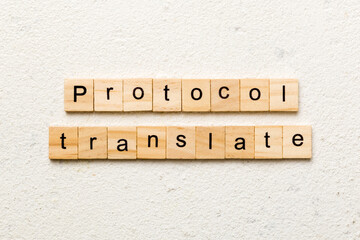 PROTOCOL translate word written on wood block. PROTOCOL translate text on cement table for your desing, concept