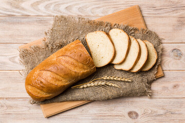 Freshly baked bread slices on cutting board against white wooden background. top view Sliced bread