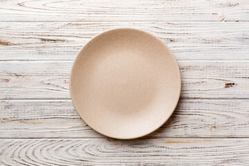 Top view of empty light plate on wooden background. Empty space for your design