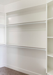 Fototapeta na wymiar Vertical White built in wall mount shelving unit in a walk in closet