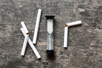 Broken cigarette on table background , No Tobacco Day with hourglass, clock health concept. time to quit smoking