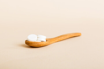 Heap of white pills on colored background. Tablets scattered on a table. Pile of red soft gelatin capsule. Vitamins and dietary supplements concept
