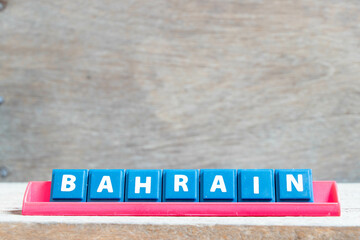 Tile alphabet letter with word bahrain in red color rack on wood background