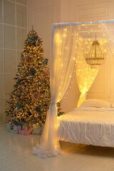 Bright glowing Christmas tree in living room in evening. Christmas tree with lights glowing garlands and gifts. Festive interior design living room with Xmas decorations. Interior design bedroom.	