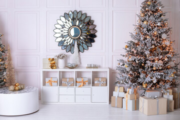 New year winter home decor. A round mirror like sun hangs on wall. Stylish white living room interior with decorated Xmas tree and wooden shelving with festive decor, many gifts. Christmas at home.	