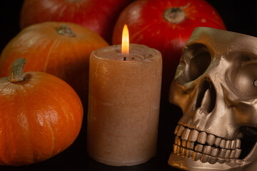 Yellow-orange pumpkins with candles and skulls on a black background the concept of Halloween and the autumn harvest of pumpkin close-up copyspace from above