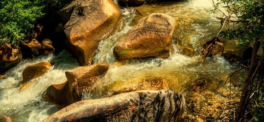Creek streaming over rocks with mysterious ancient petroglyphs