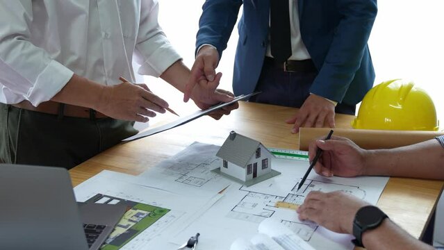 Businessman and architect meeting for planing and checking house design and house model and secretary takes notes, the architect design working drawing sketch plans blueprints