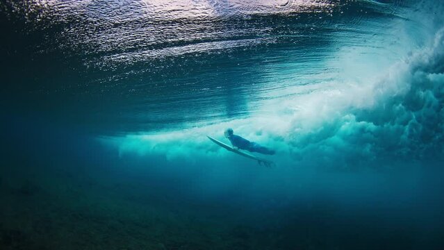 Surfer dives under wave. Speed warped footage of the surfer doing duck dive in the clear water