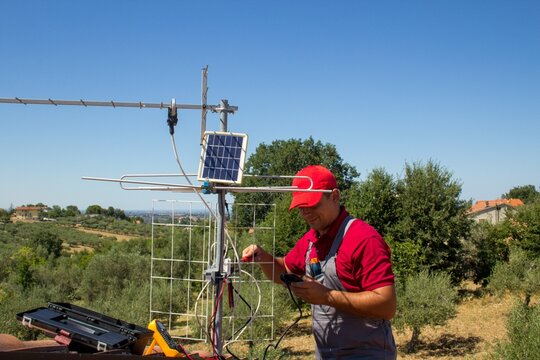 Male Trying To Charge His Phone From The Little Solar Panel In The Countryside