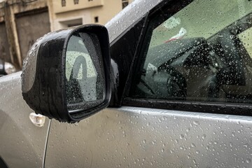 Naklejka premium Raindrops on white car side rear-view mirror