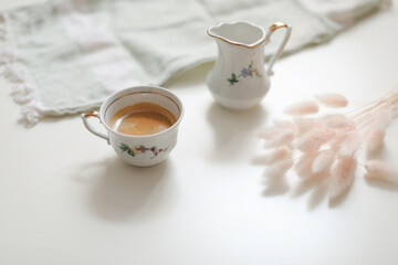 cup with coffee and milk jug on a white wooden background, closeup. Energy breakfast, morning routine concept