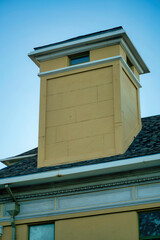 Modern chimney design with wooden pannels with metal pinacle with gray roof tiles on side of house or building in neighborhood