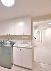Vertical Interior of a laundry room with an open white door and a view of the hallway