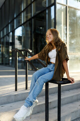 Portrait of teenage girl sitting on stairs, urban street, sunlight