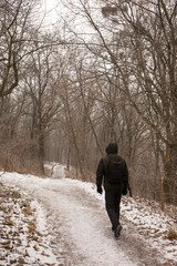 Fototapeta na wymiar A man with a backpack walks in the park in winter