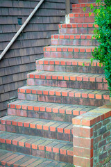 Row of red brick stairs with decorative cement on a house or home entry near front door with black metal gaurd hand rail