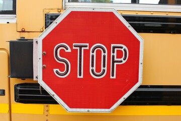 Closeup of a red Stop sign on a yellow school bus