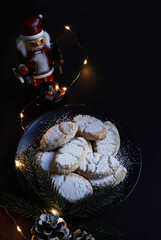 Ricciarelli, tipico dolce natalizio senese a base di mandorle su fondo scuro. Decorazioni natalizie. Dolci della tradizione italiana.